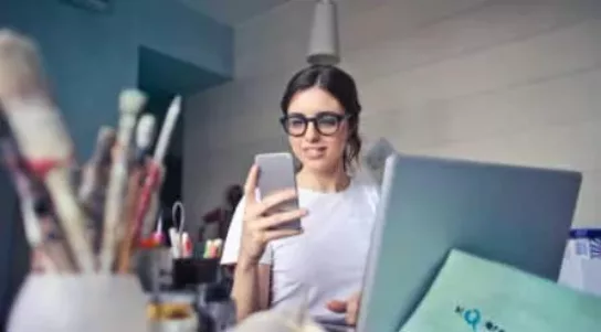 and artist looks at her mobile in a studio